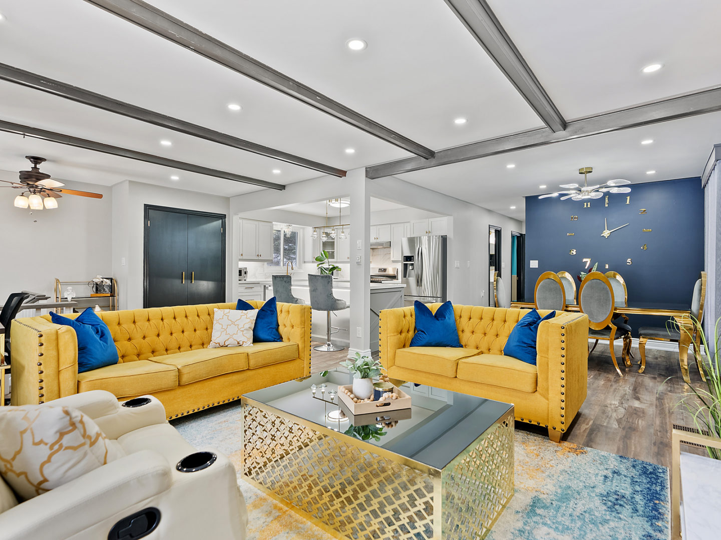 An open-concept living room area that flows into a dining space. Navy and yellow accent the space with bold colour.