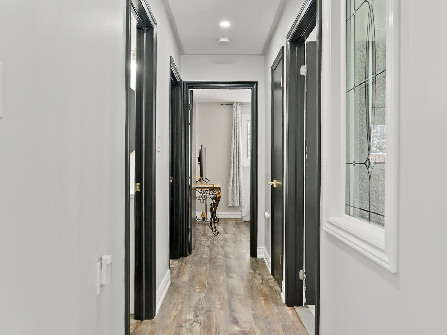 A narrow hallway with doorframes that have black-painted trim.
