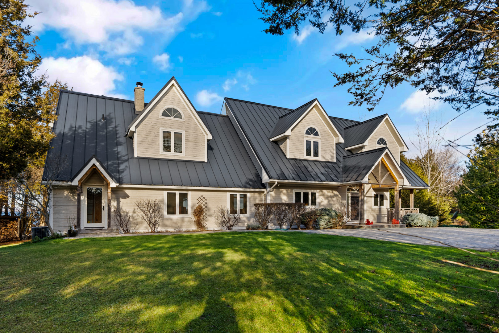 A large two-story house with a big grass lawn and a large brick driveway.