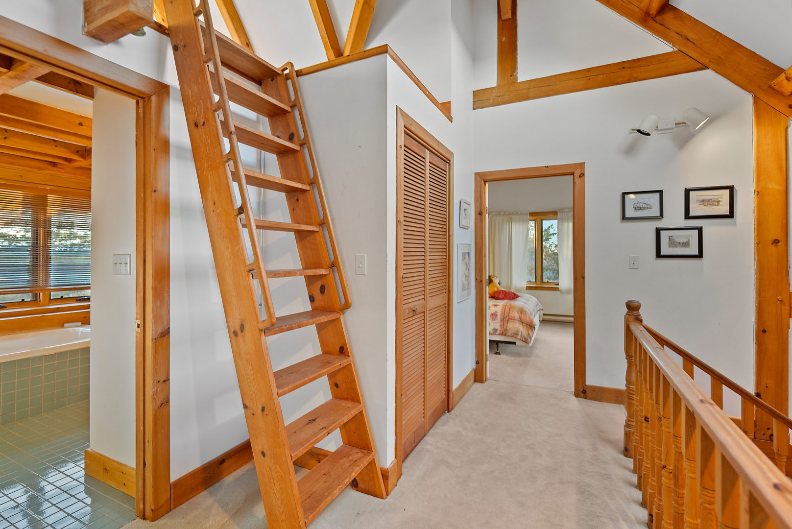 A bright upstairs landing area with a small hallway leading to a bathroom and a bedroom.