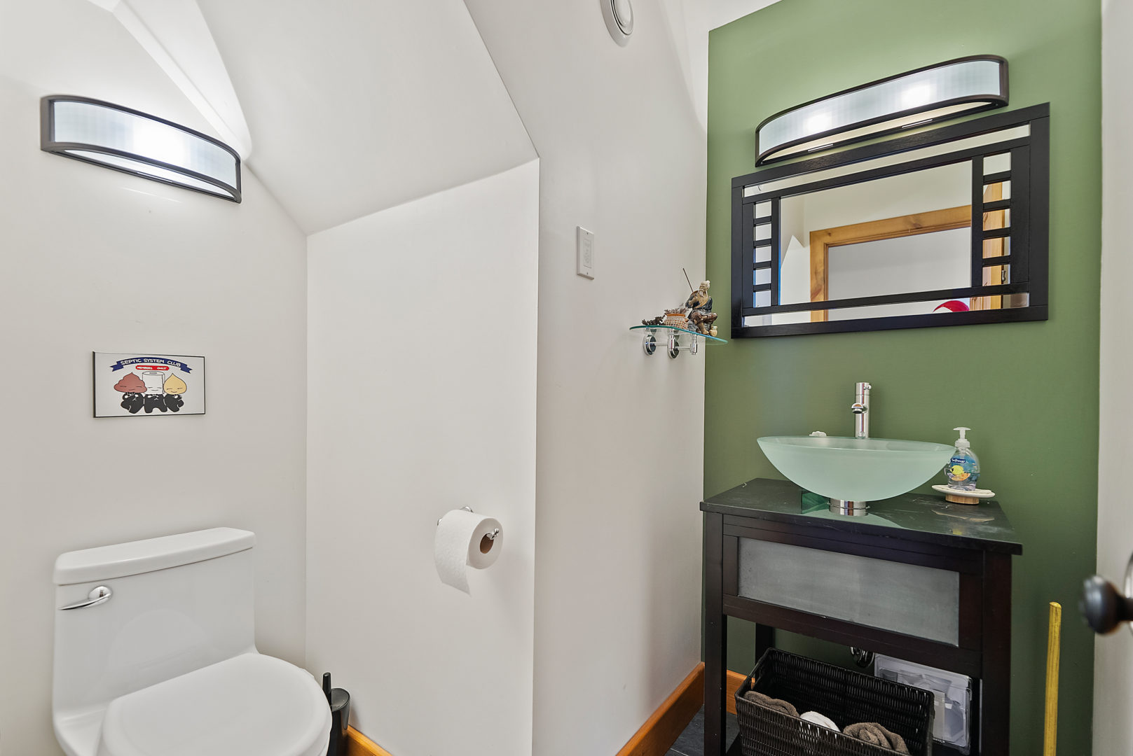 A small bathroom with a toilet, a sink, and a green accent wall.