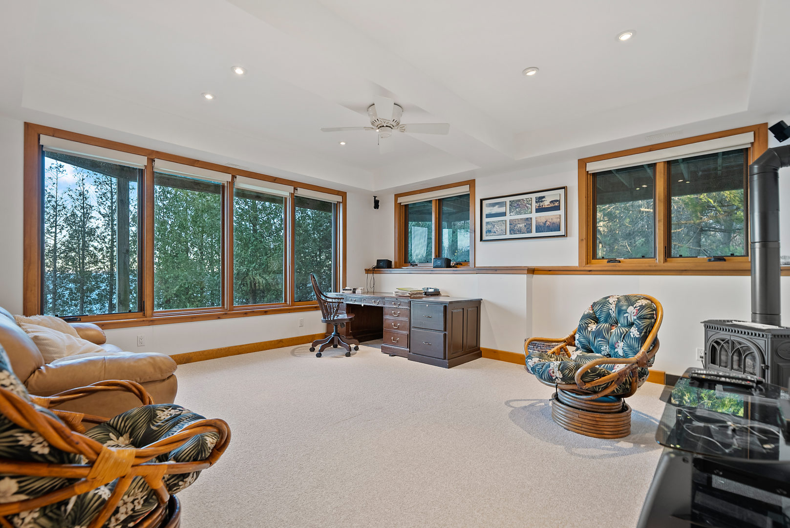 A large office area with a small deck in the corner and two basket chairs on either side of the room. Large windows throughout the room.