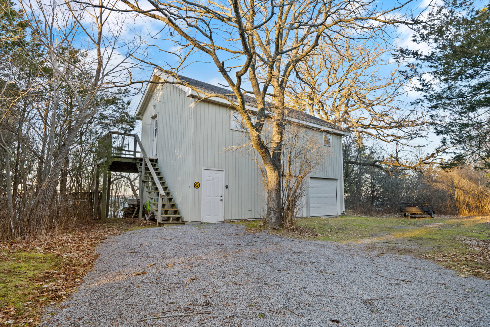 A small guest house sits behind a rocky gravel driveway area.