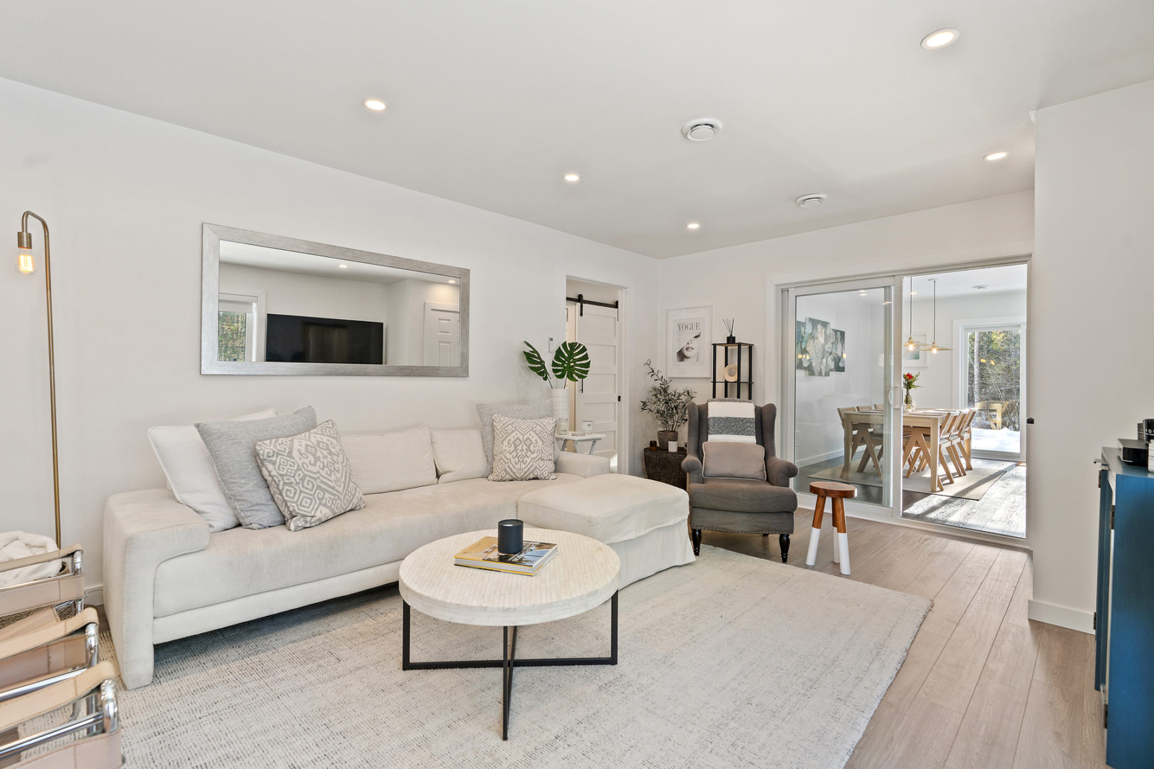 A bright living space with a couch, leading into a sectioned-off dining area.