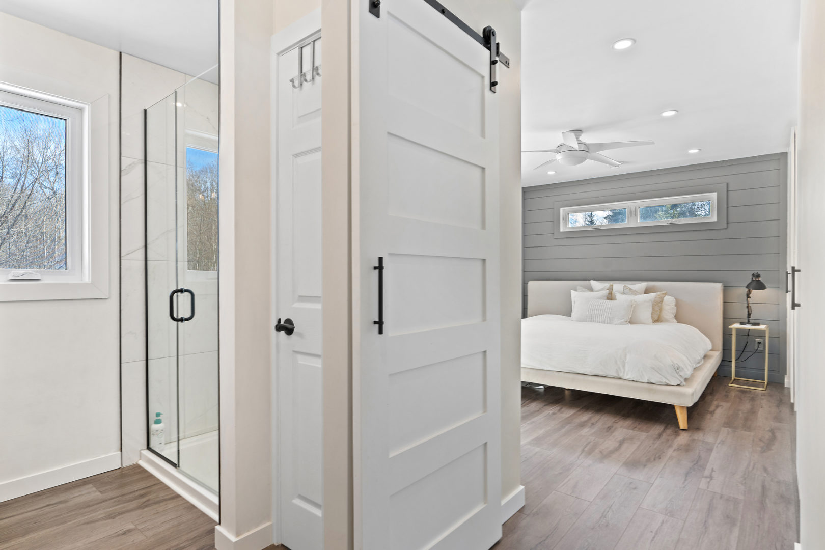 A bright bedroom space with a large bed and an ensuite bathroom that has a walk-in shower.