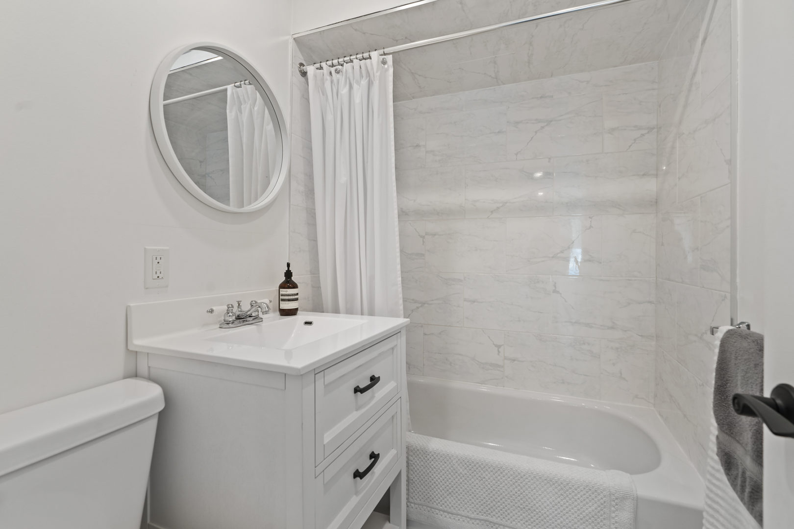 A modern bathroom with a toilet, a sink, and a shower-tub combo.