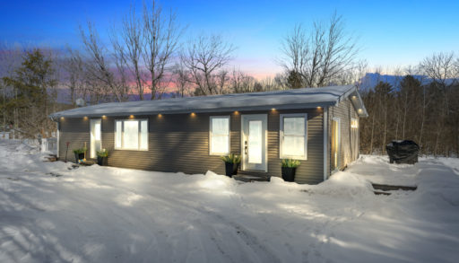 A cottage bungalow at night, lit up with plenty of exterior lights.