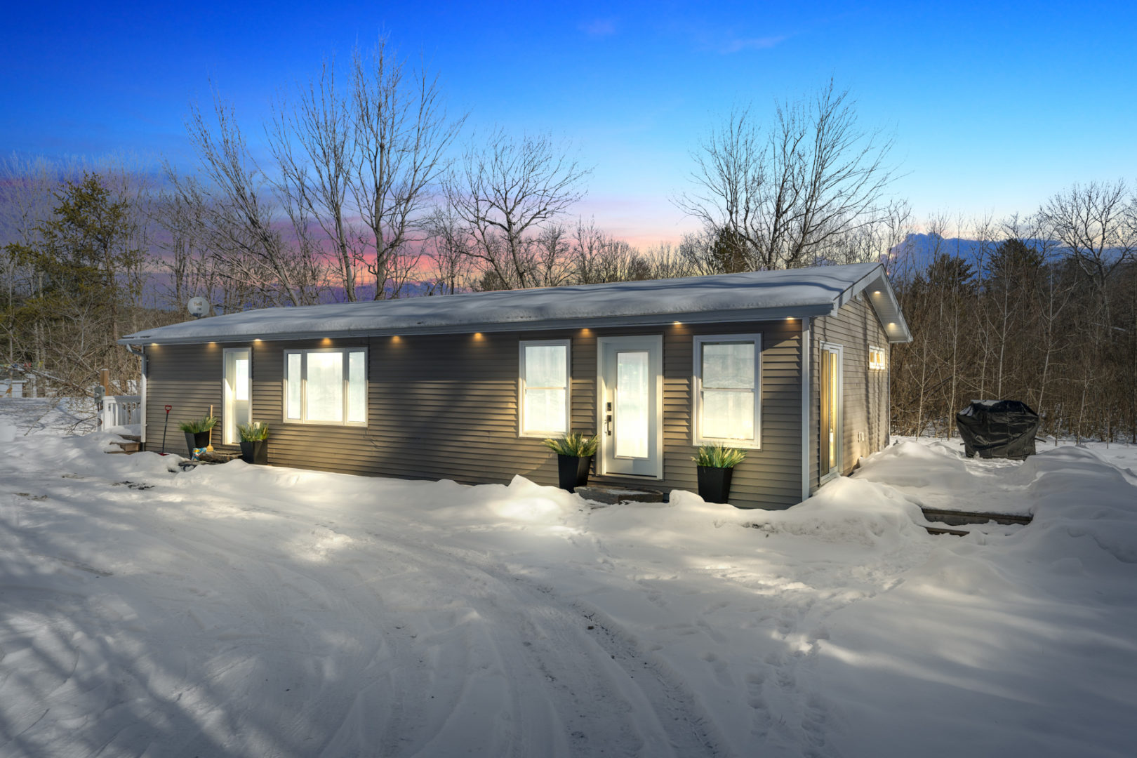 A cottage bungalow at night, lit up with plenty of exterior lights.