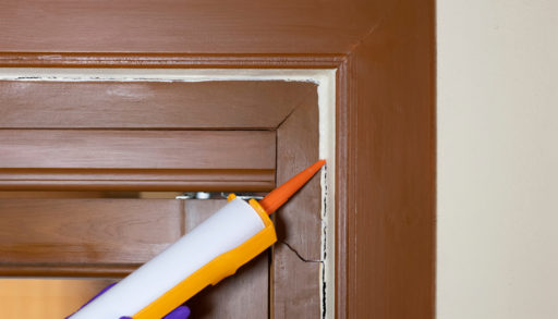 Close-up of someone applying caulk around a door frame