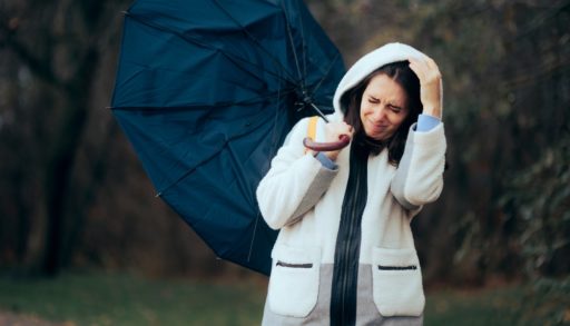 A woman struggling to hold an umbrella in a wind storm