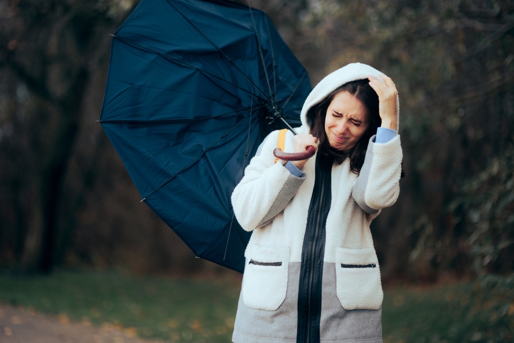 A woman struggling to hold an umbrella in a wind storm