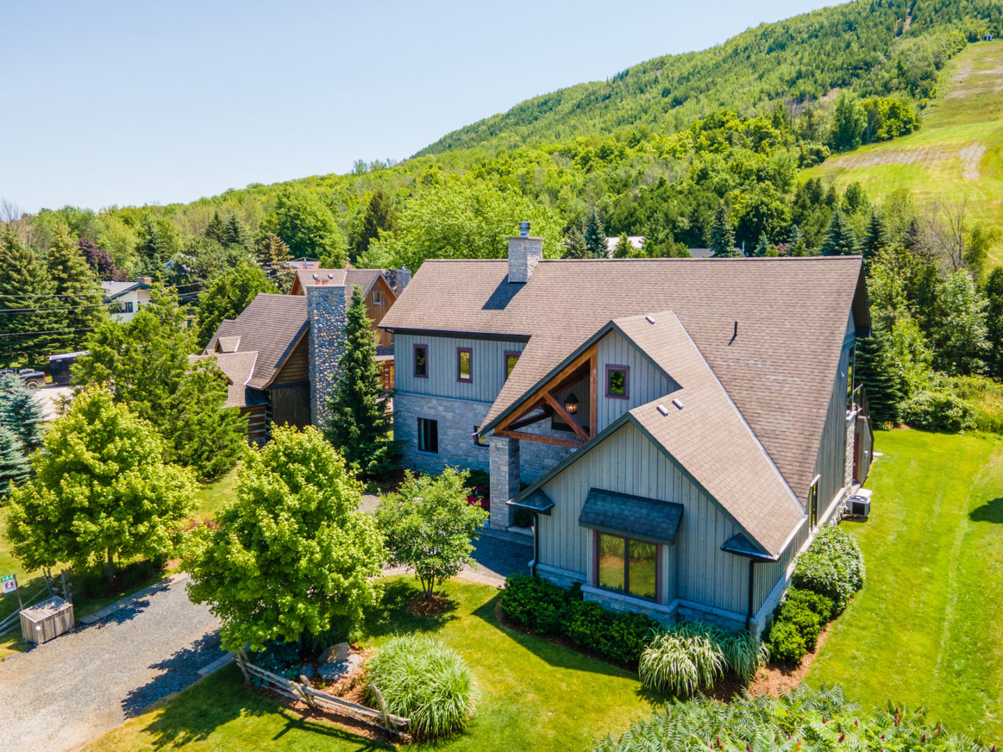 A large, two-story house that sits at the base of a big sloping mountain.