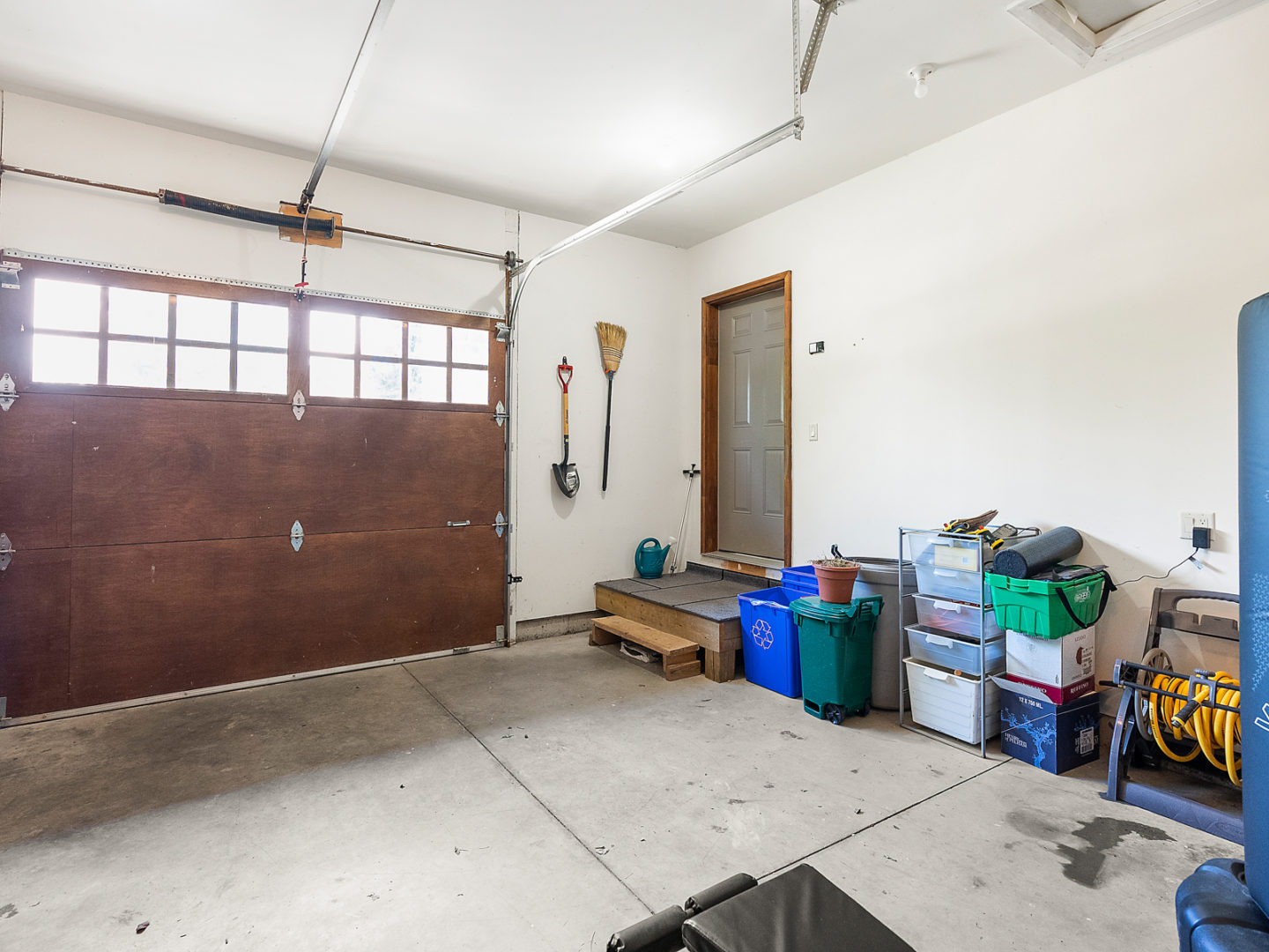Inside a garage, pretty bare with a door leading into a house.