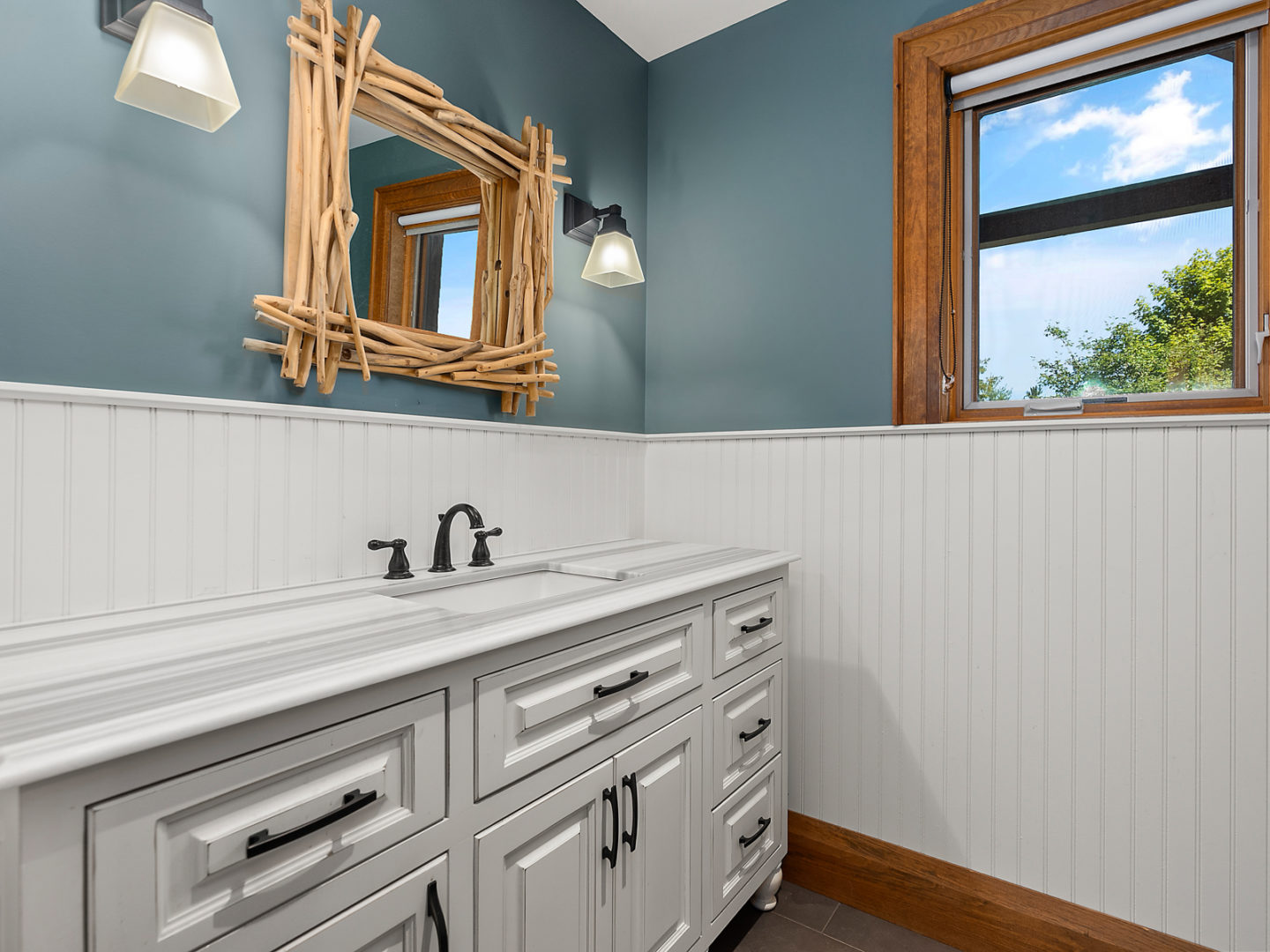 A clean, bright bathroom with a large sink and an accent mirror.