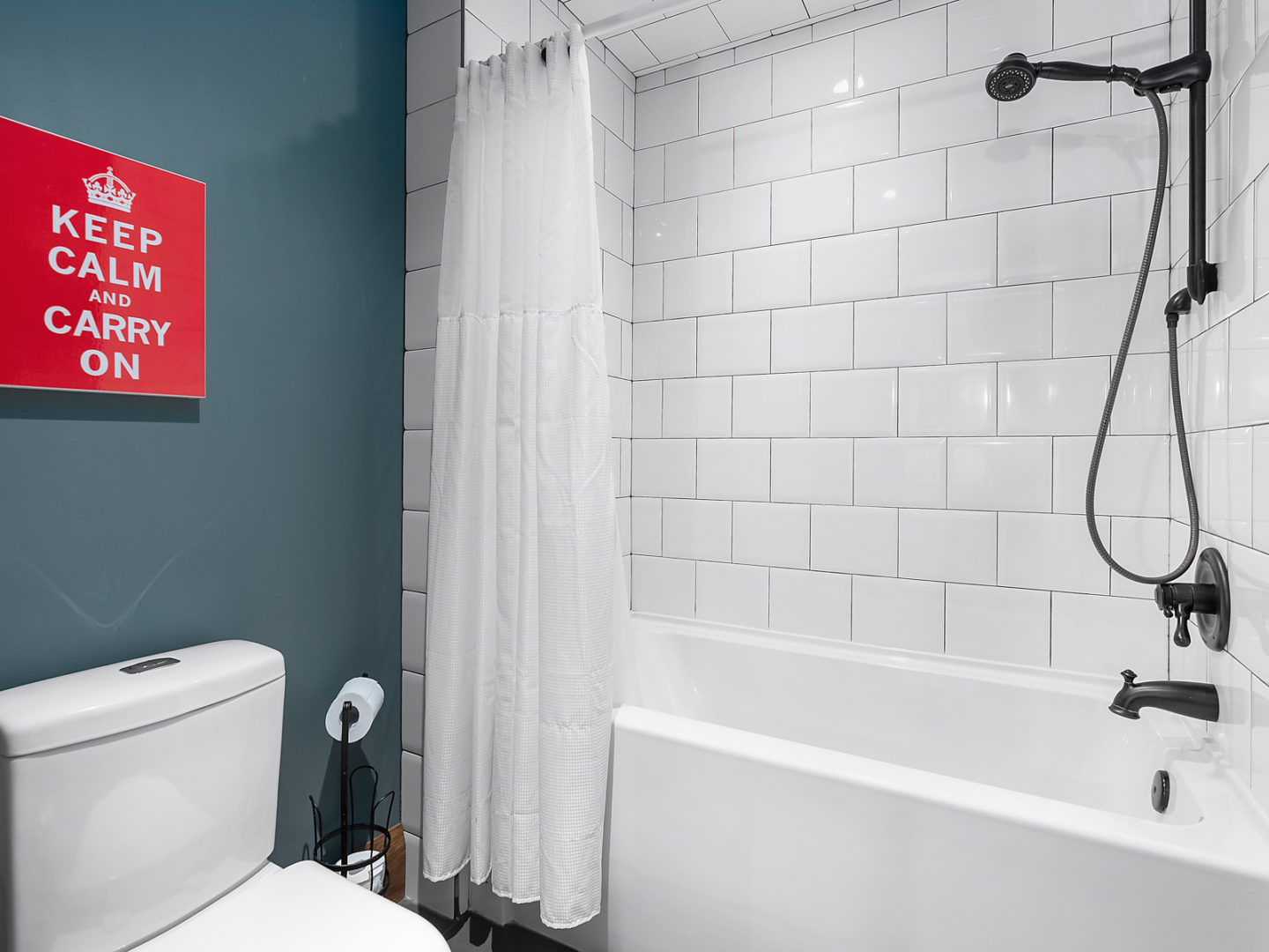 A bathroom with a toilet and a bathtub with a shower.