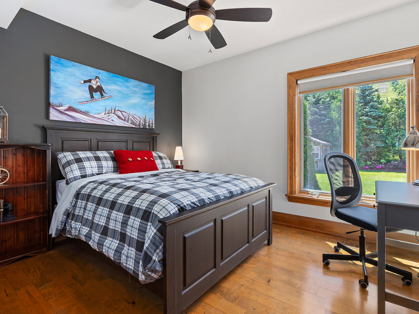 A bedroom with a large bed, hardwood floors, and a big window.