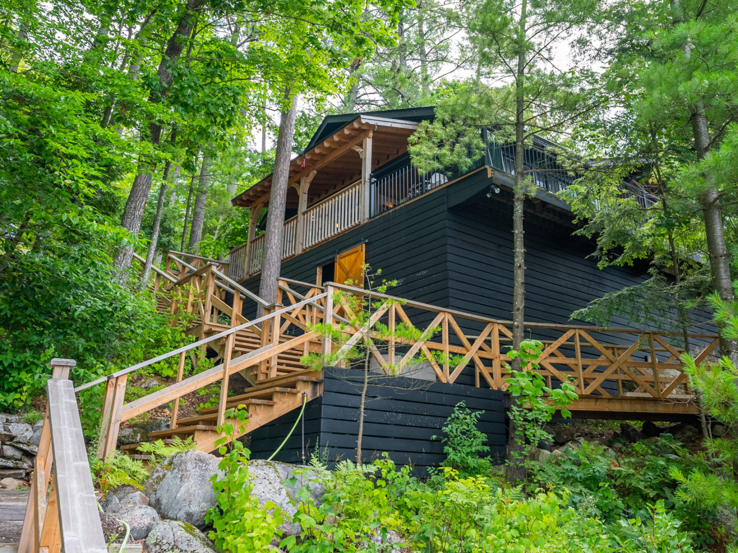 A long, zig-zagging wooden stairway leading from lake level to a large luxury cottage.