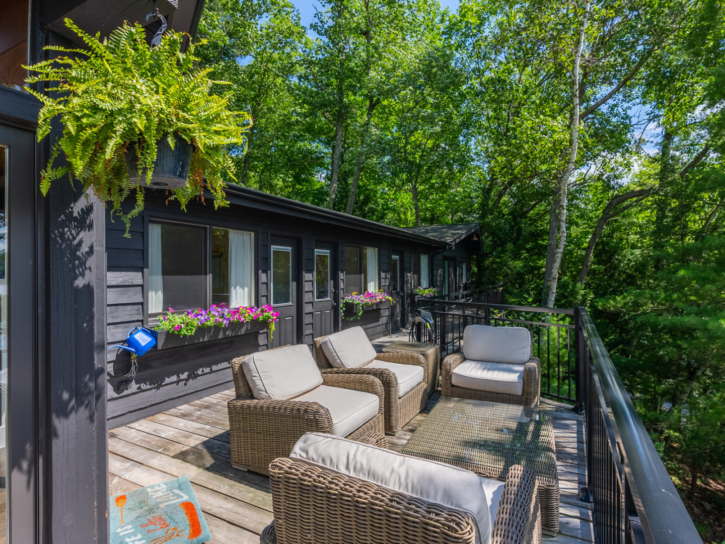 An outdoor living space with couches, located on part of a wrap-around deck on a large cottage.