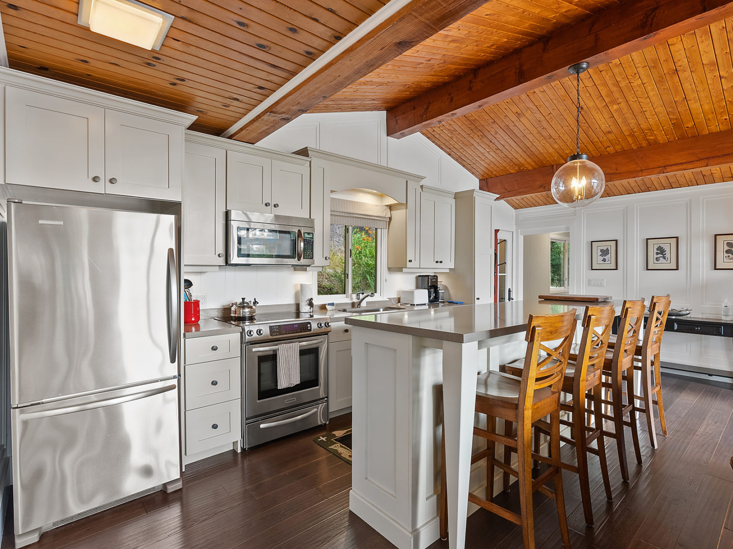 A modest-sized cottage kitchen with an island, barstools and modern appliances.
