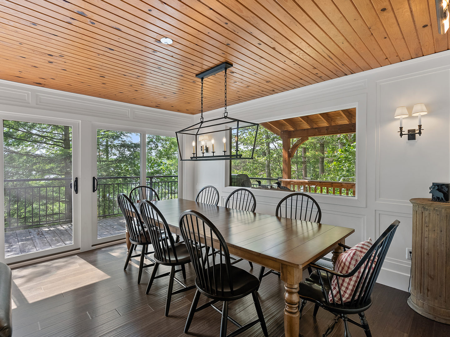 A dining area in a luxury cottage, with a table and chairs and a double-door exit to the outside deck.