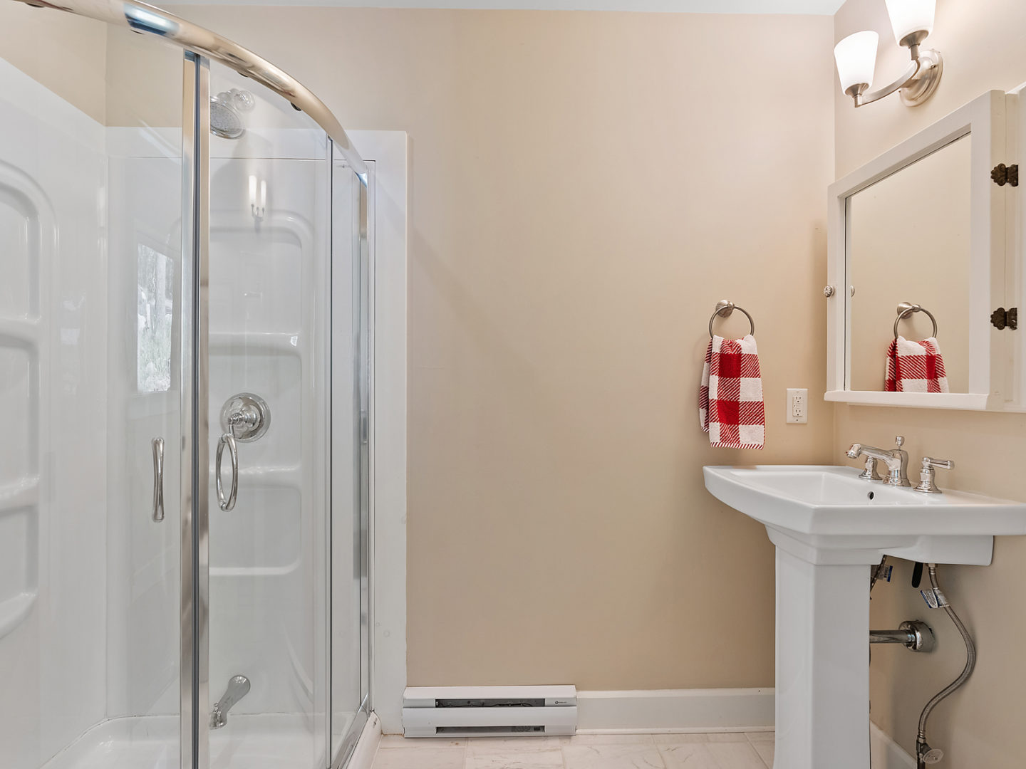 A modest bathroom with a sink, a toilet and a walk-in shower.