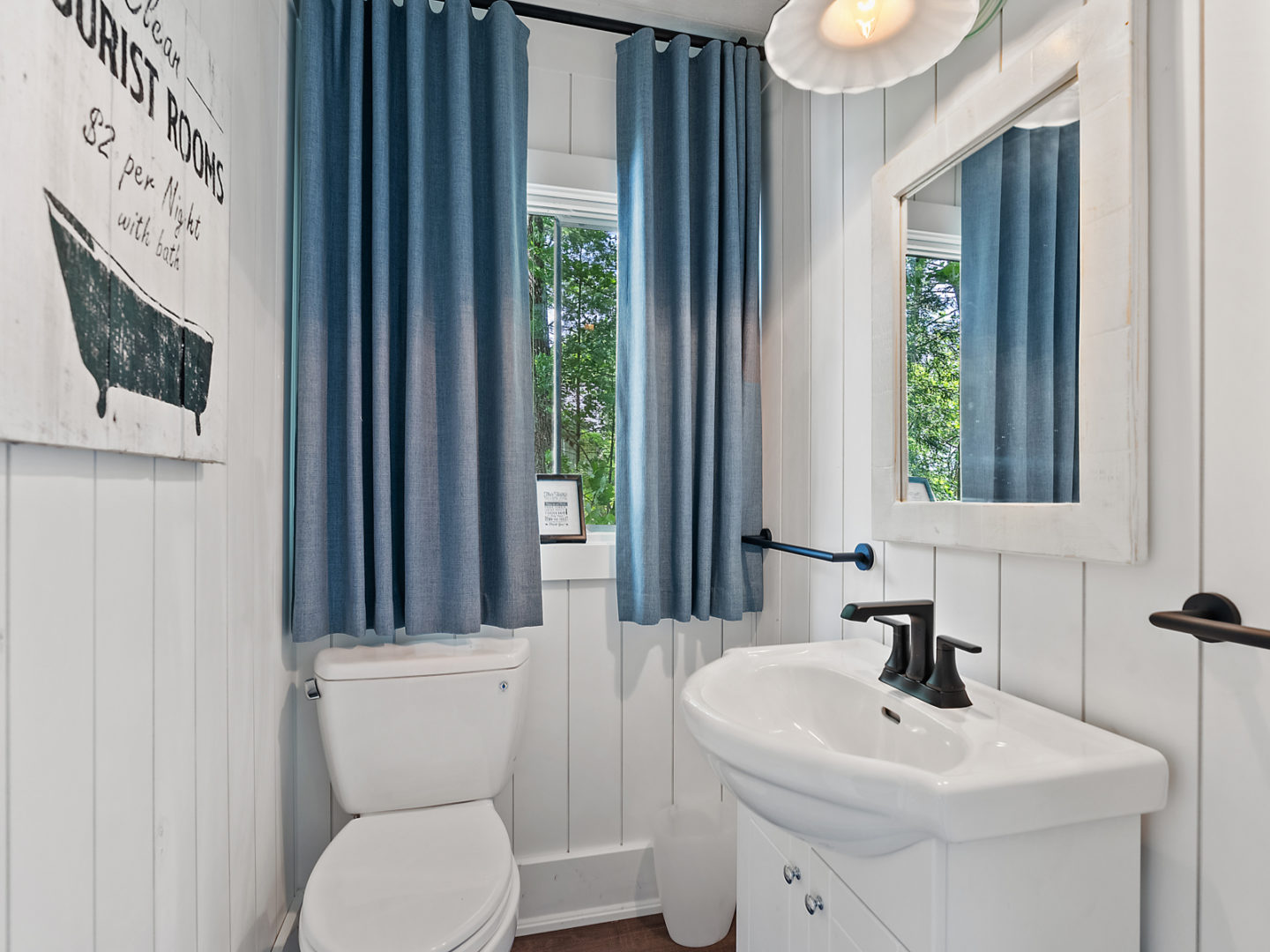 A small bathroom with a toilet and a sink, in a bunkie.