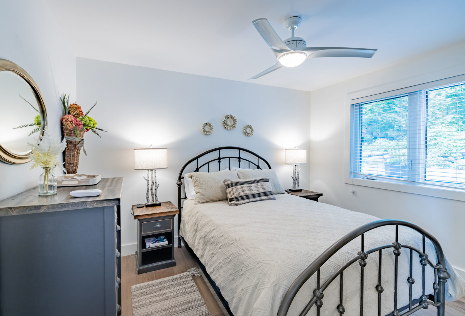 A medium-sized bedroom with a bed, a dresser, and a ceiling fan.