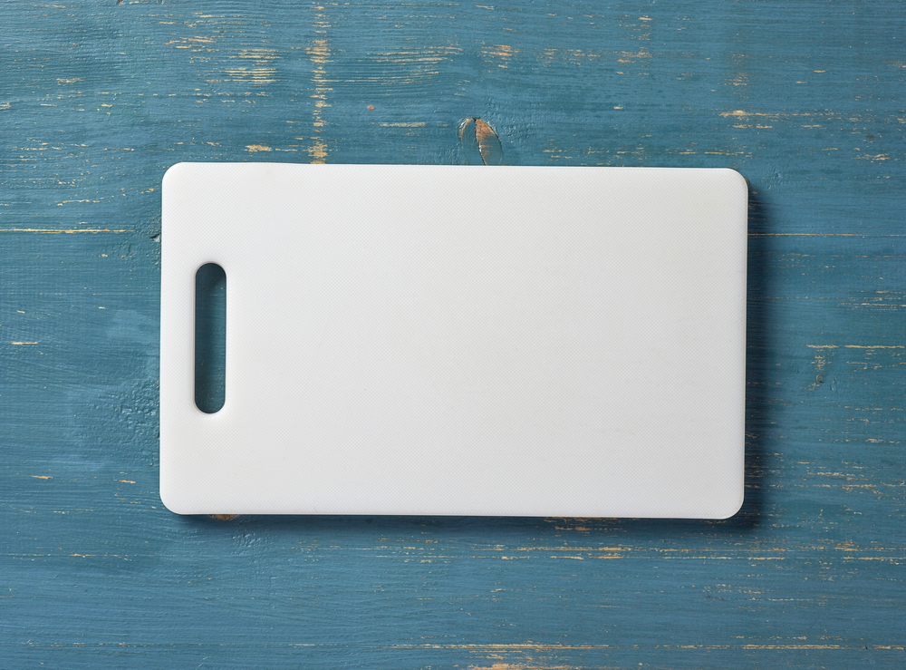 A white plastic cutting board on a blue table