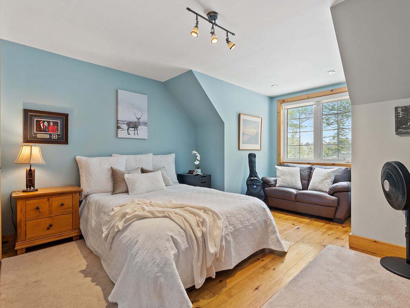 A bright bedroom with blue walls, a large bed, and a window seat.