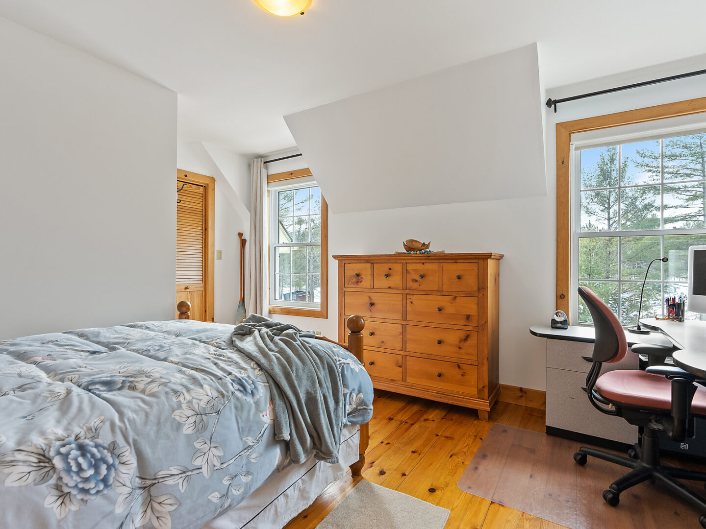 A bright room with a single bed, a dresser, and a desk.