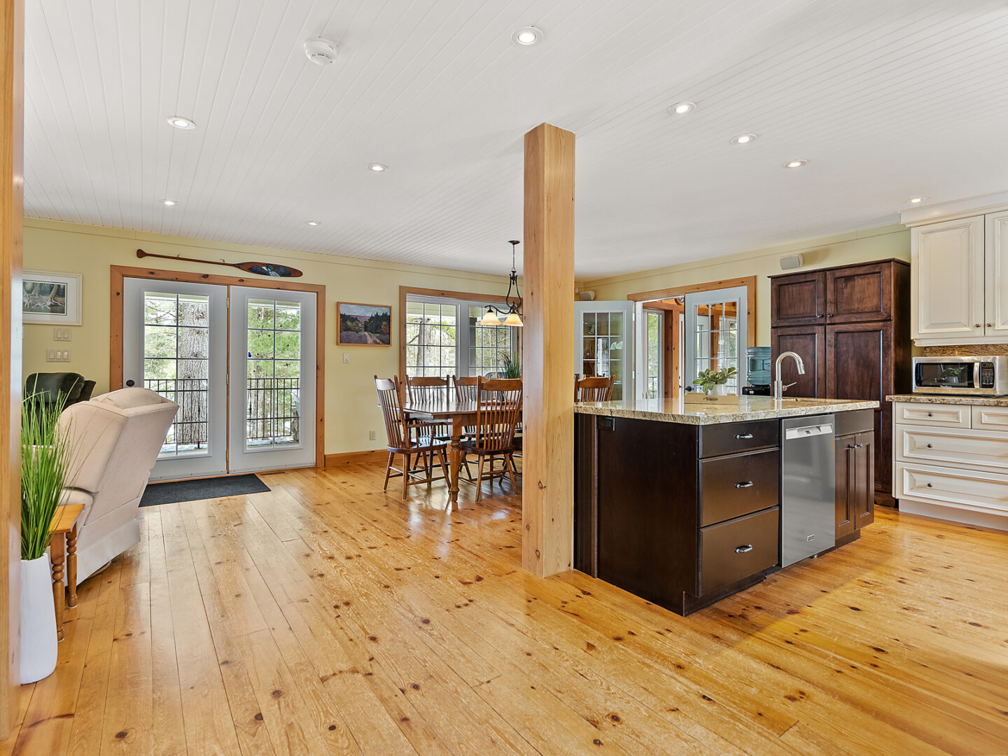 A bright, spacious living area of a home, featuring a kitchen island and a dining room table.