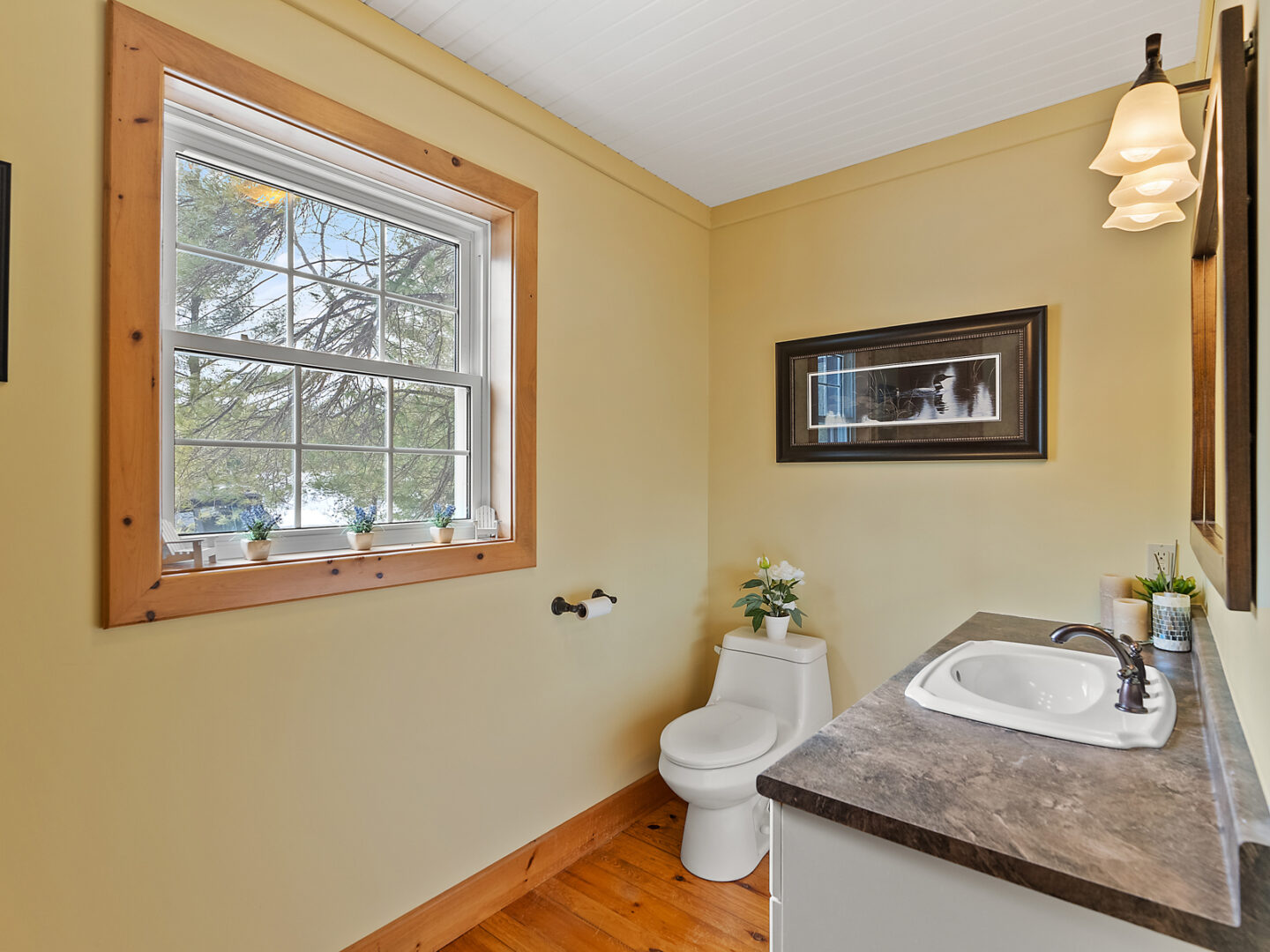 A small bathroom with a toilet, a sink, and a big window.