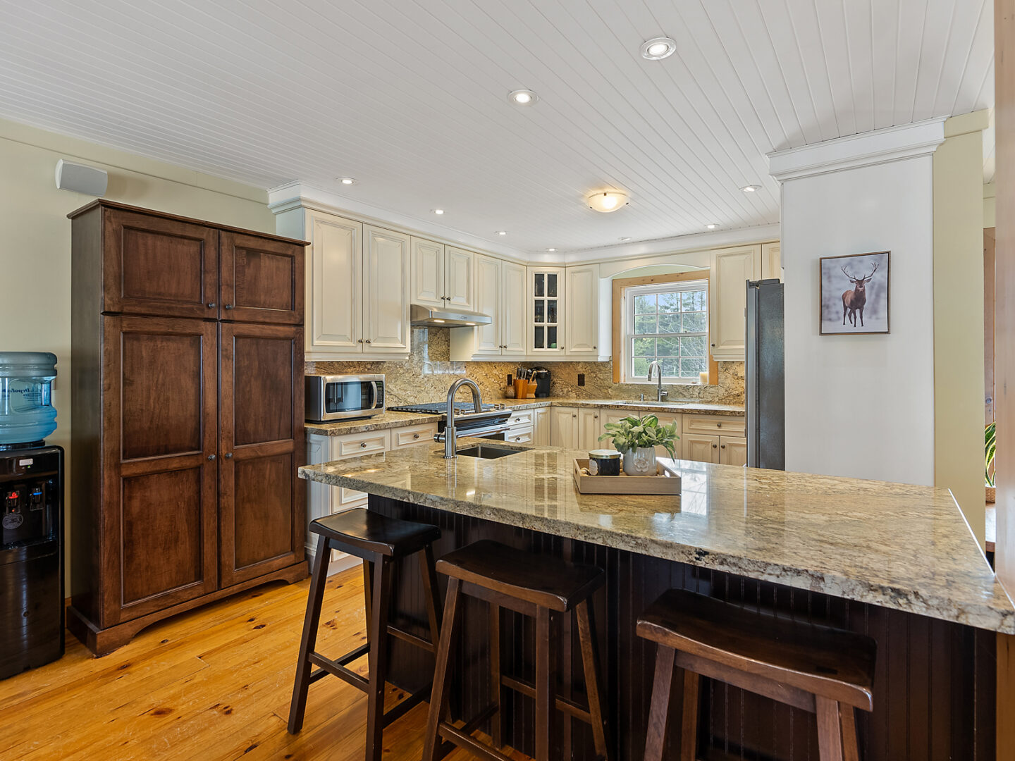 An open-concept kitchen space with warm hardwood floors and contrasting dark wood and cream coloured cabinets.