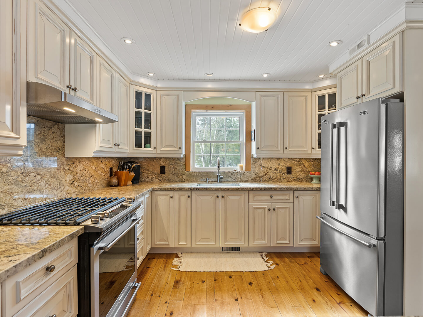 A kitchen space with cream coloured cabinets, stainless steel appliances and lots of counter space.