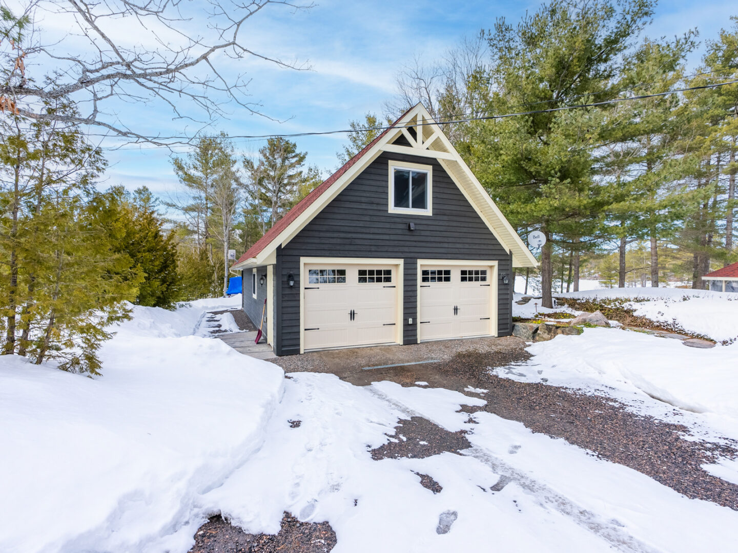 A detached two-car garage with a navy exterior and white doors.