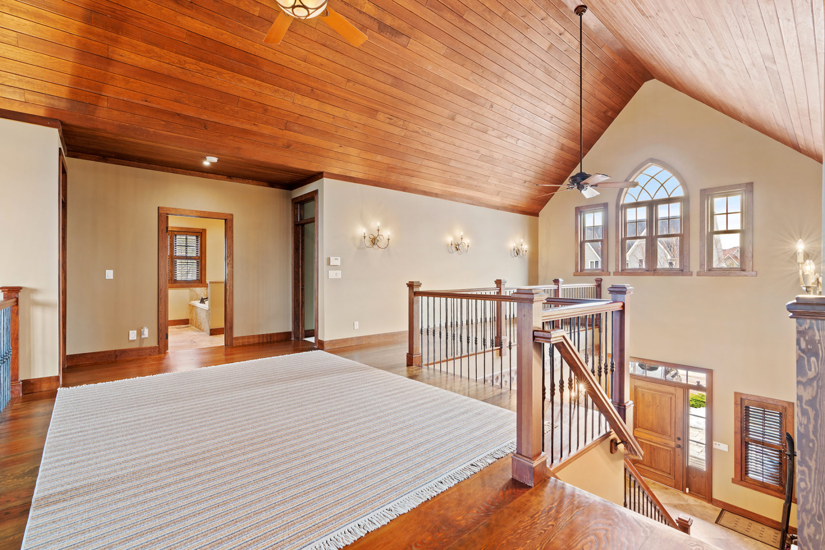 A wide second floor hallway with a balcony looking over the main level of the home.
