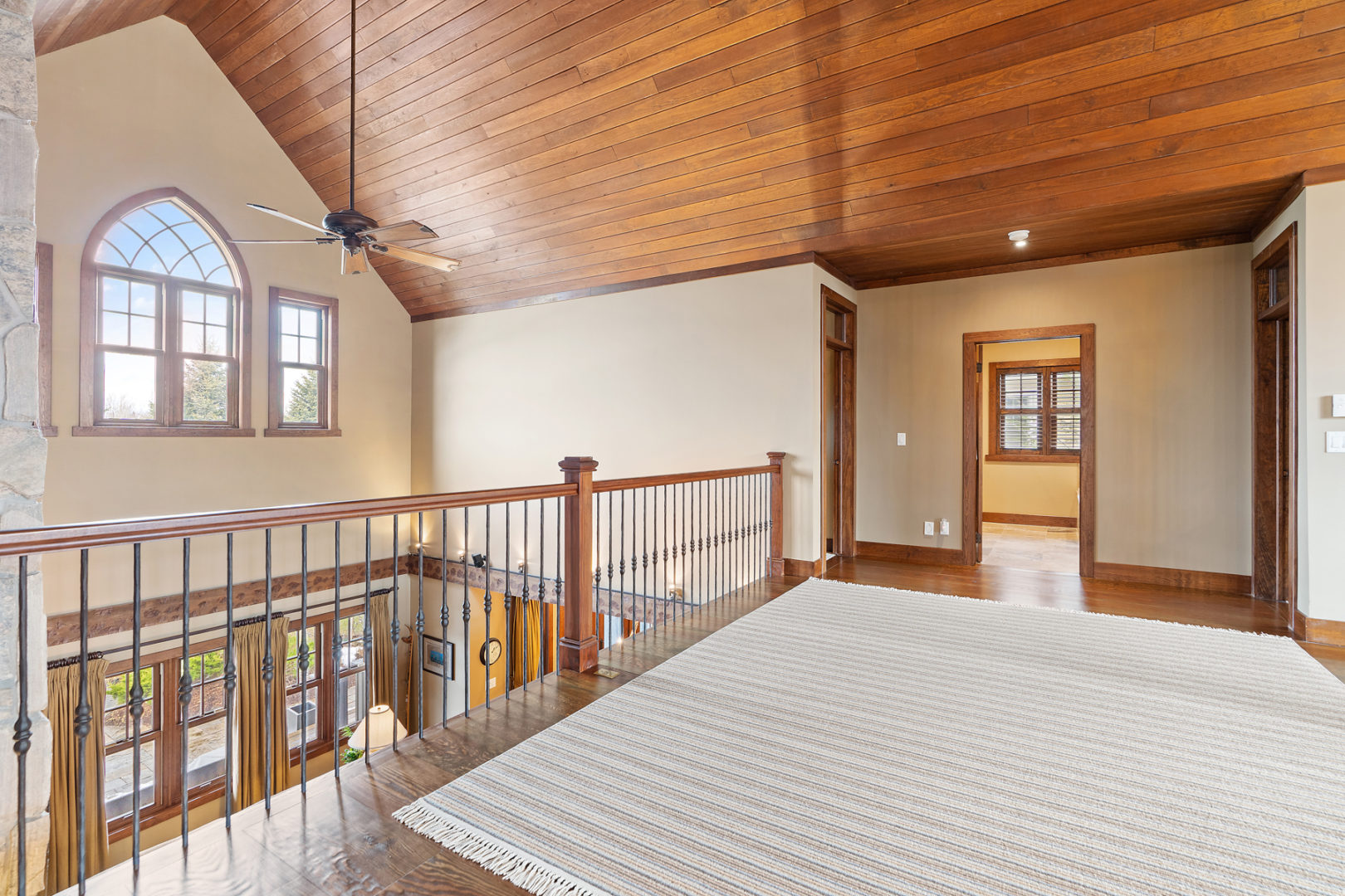 A wide second floor hallway with a balcony looking over the main level of the home.