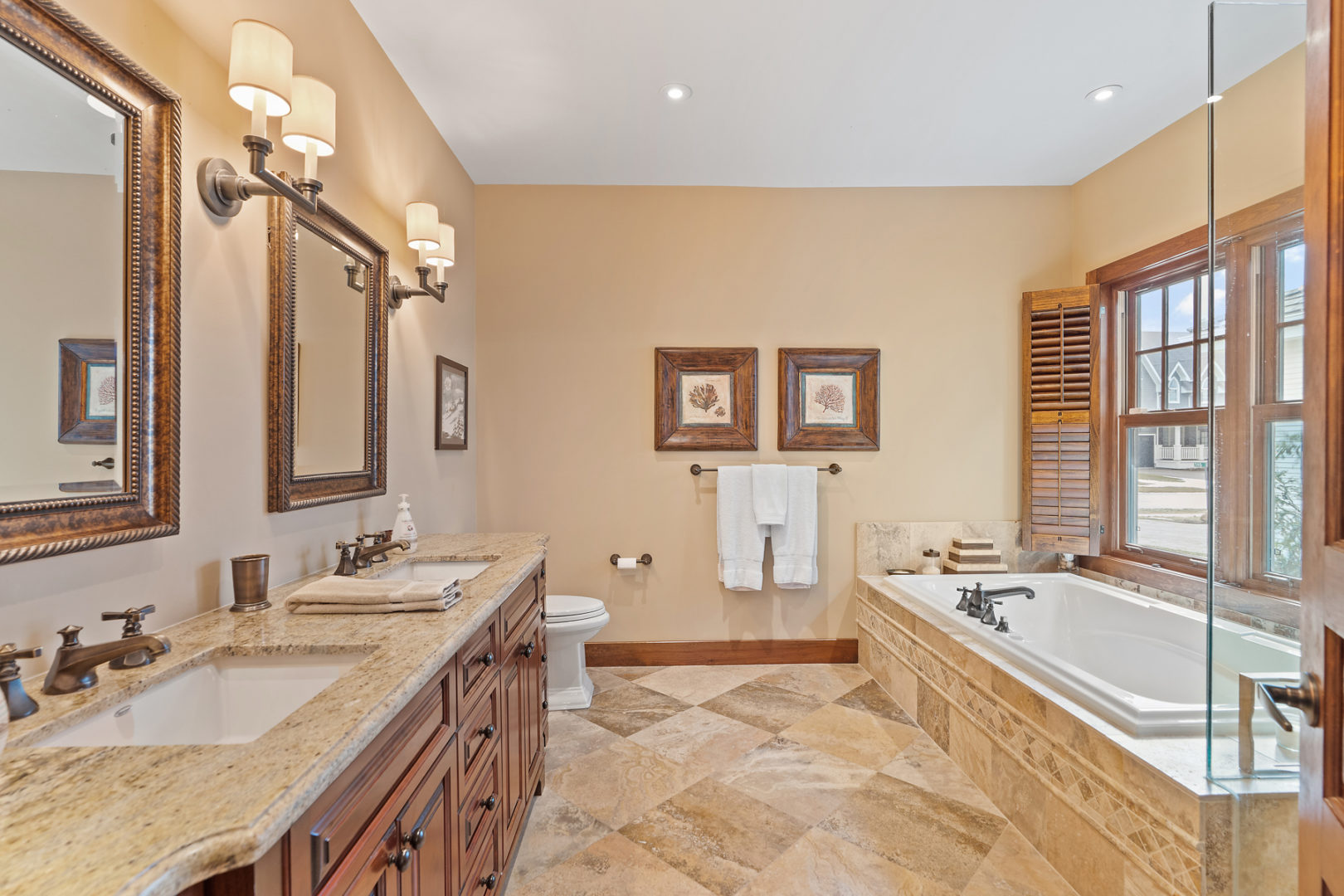 A spacious primary ensuite bathroom with a toilet, double sinks, a soaker tub, and a walk-in shower.