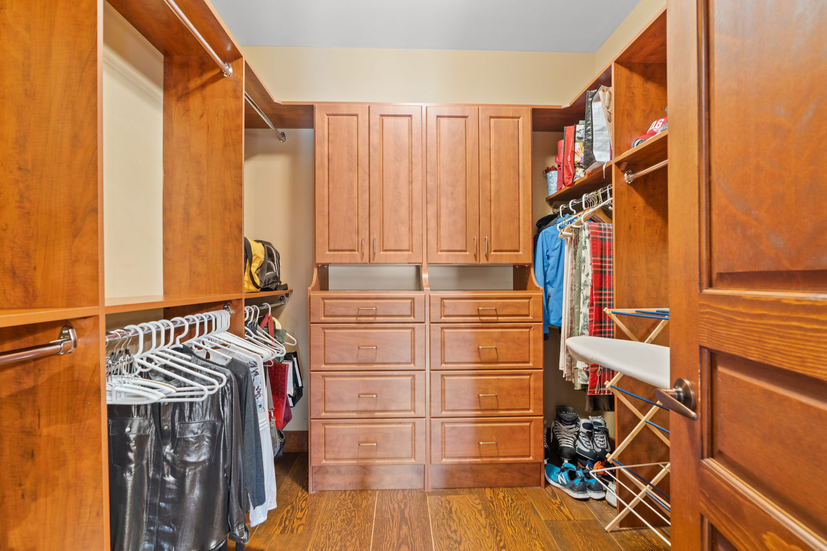 A large walk-in closet with warm wooden cupboards and drawers.