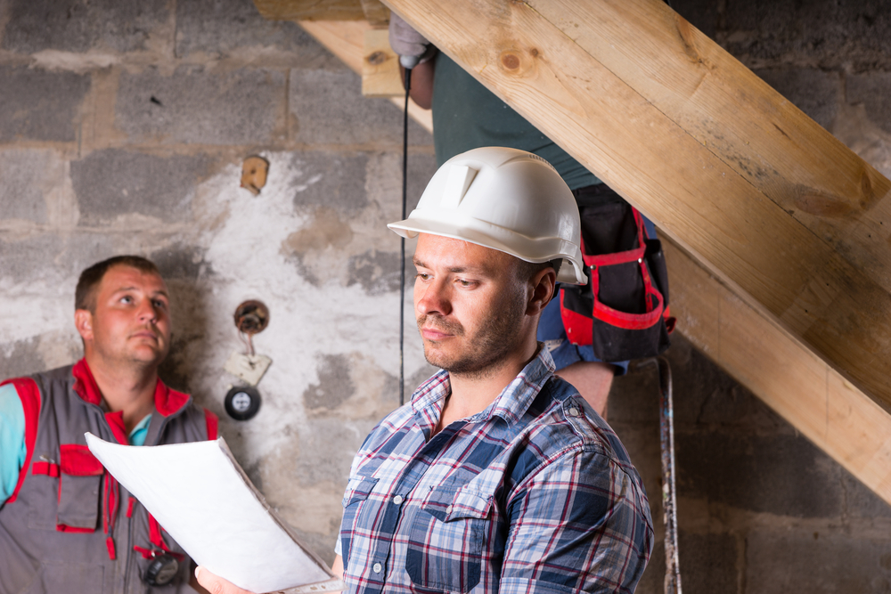 Three men in the middle of finishing a basement