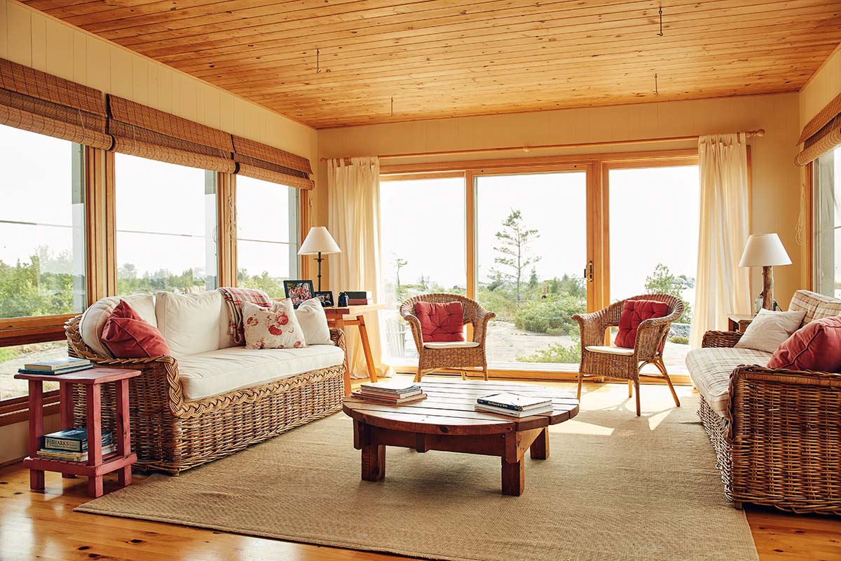 Living room set up at the cottage with large bay windows letting in lots of sunlight. Concept design for cool and sustainable chairs, two chairs, a couch, and a table inside this living room