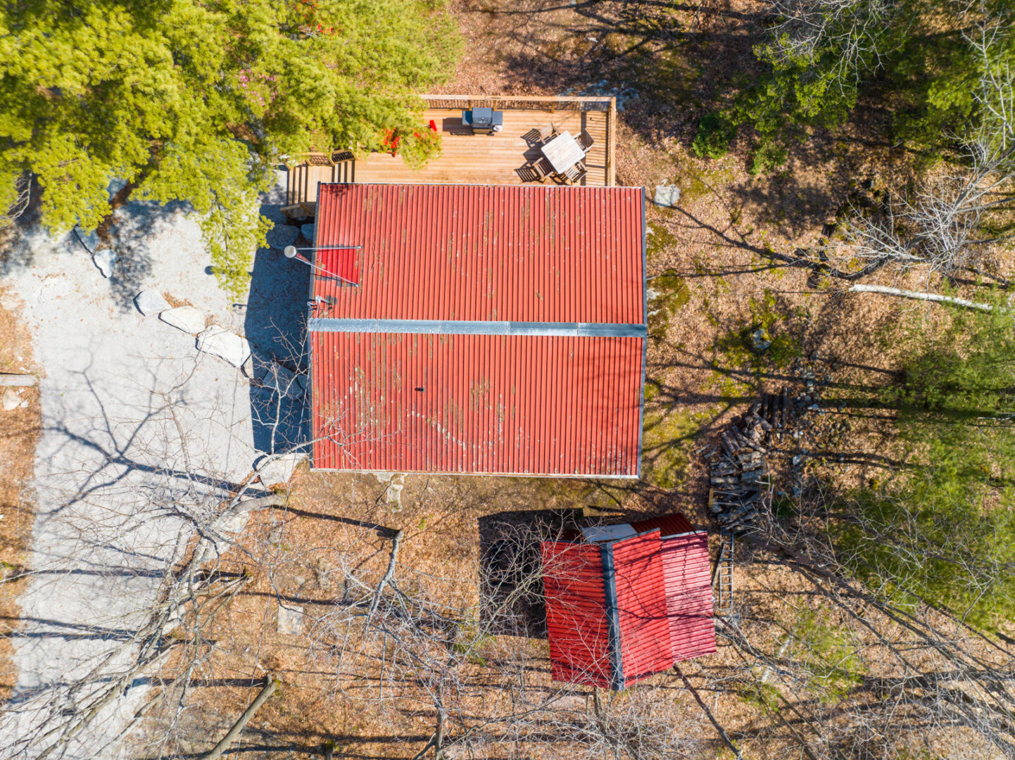 Aerial view of a small cottage with a red roof and a smaller shed with a red roof beside it.