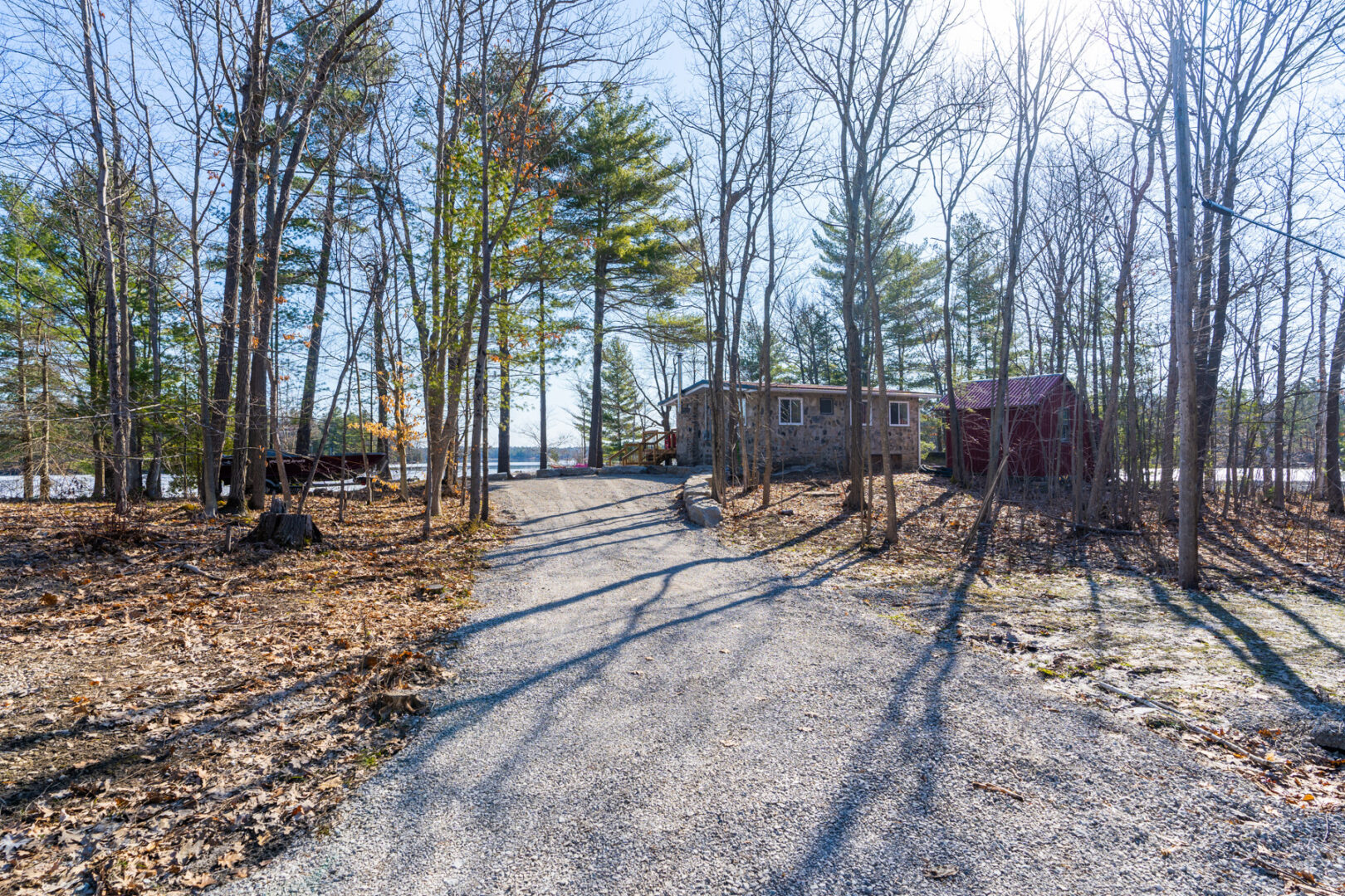 A long gravel driveway leading to a small cottage property.
