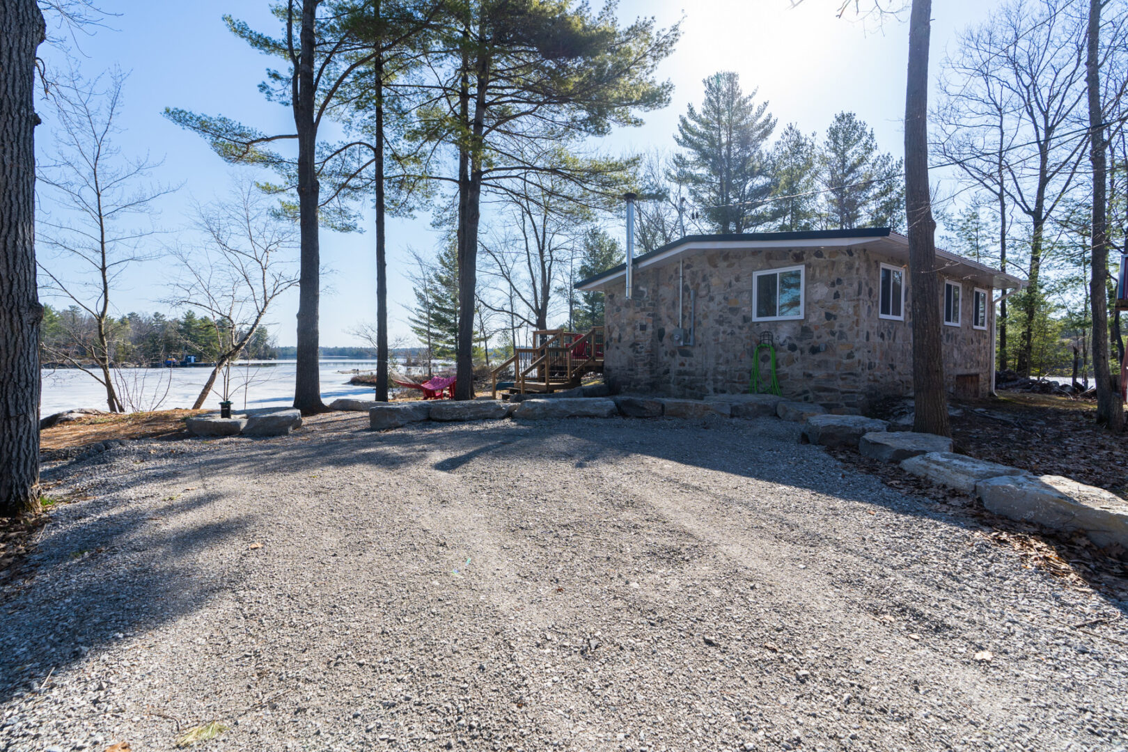 A large gravel driveway area in front of a small cottage, with lots of parking space.