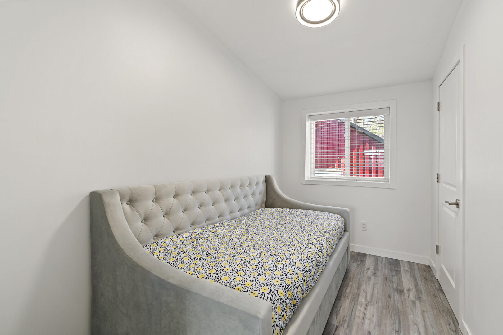 A small bedroom with a daybed and a little window.