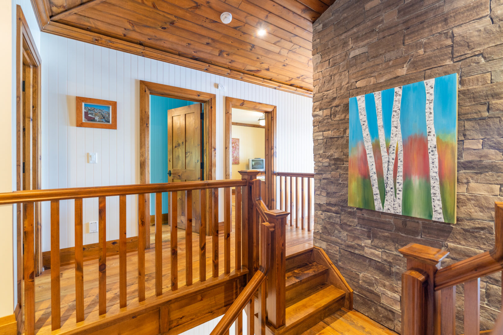 A landing at the top of a staircase with a wooden railing and doorways leading to other rooms.