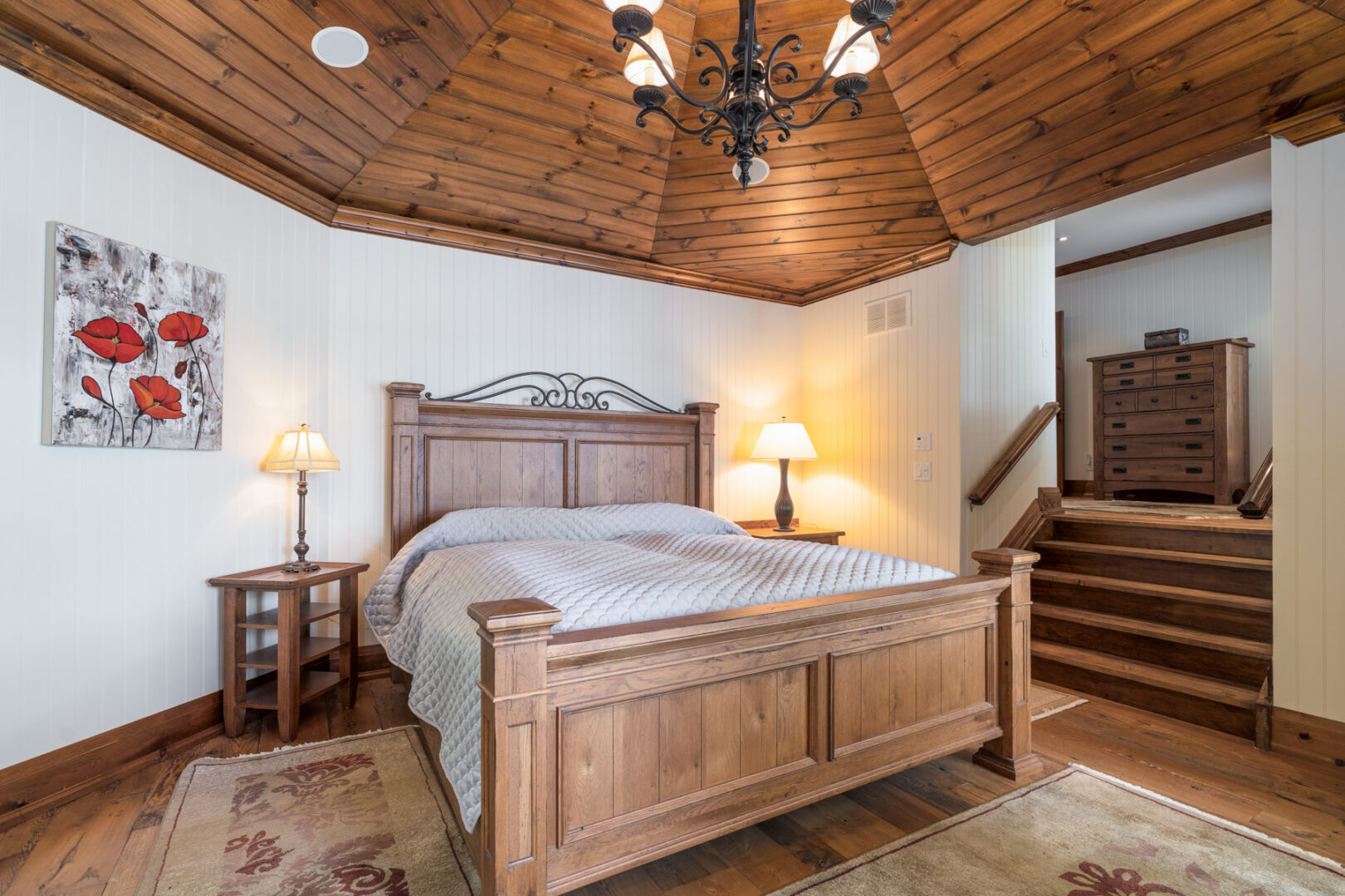 A primary bedroom space with a large bed and wood ceiling accents.