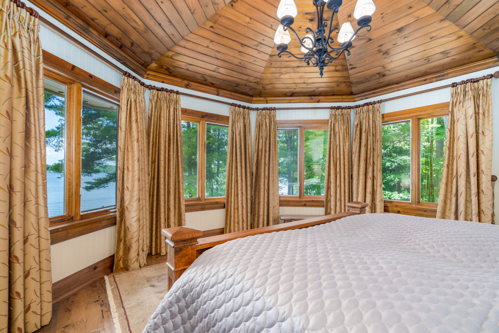 View from the bed in a large primary bedroom, looking out to a wall of windows curving around the bed.