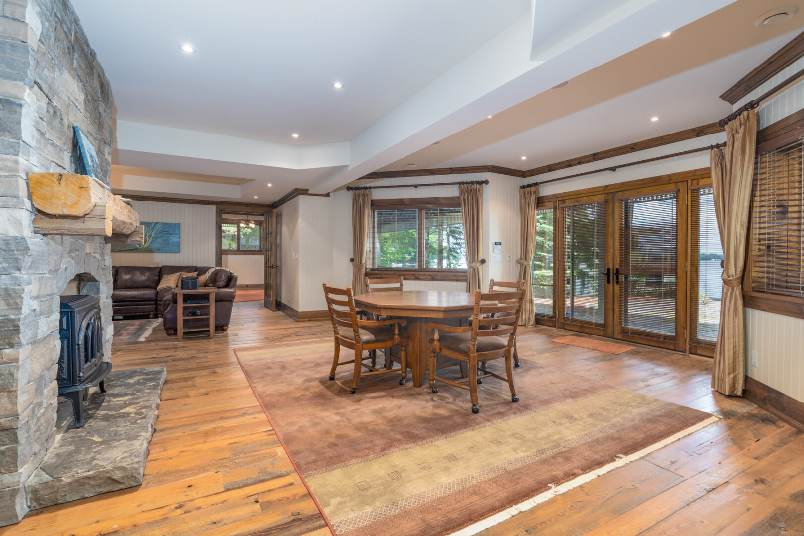 A spacious lower-level living area with a dining table and chairs in the middle of the room. Double doors lead to an outdoor space.