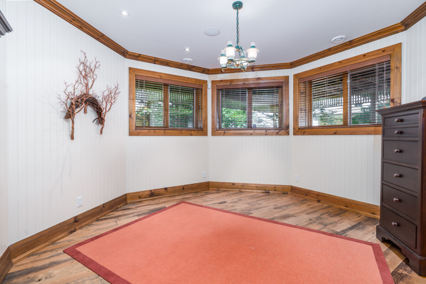 An empty room on the lower-level of a lakeside home with windows along the top of the walls.